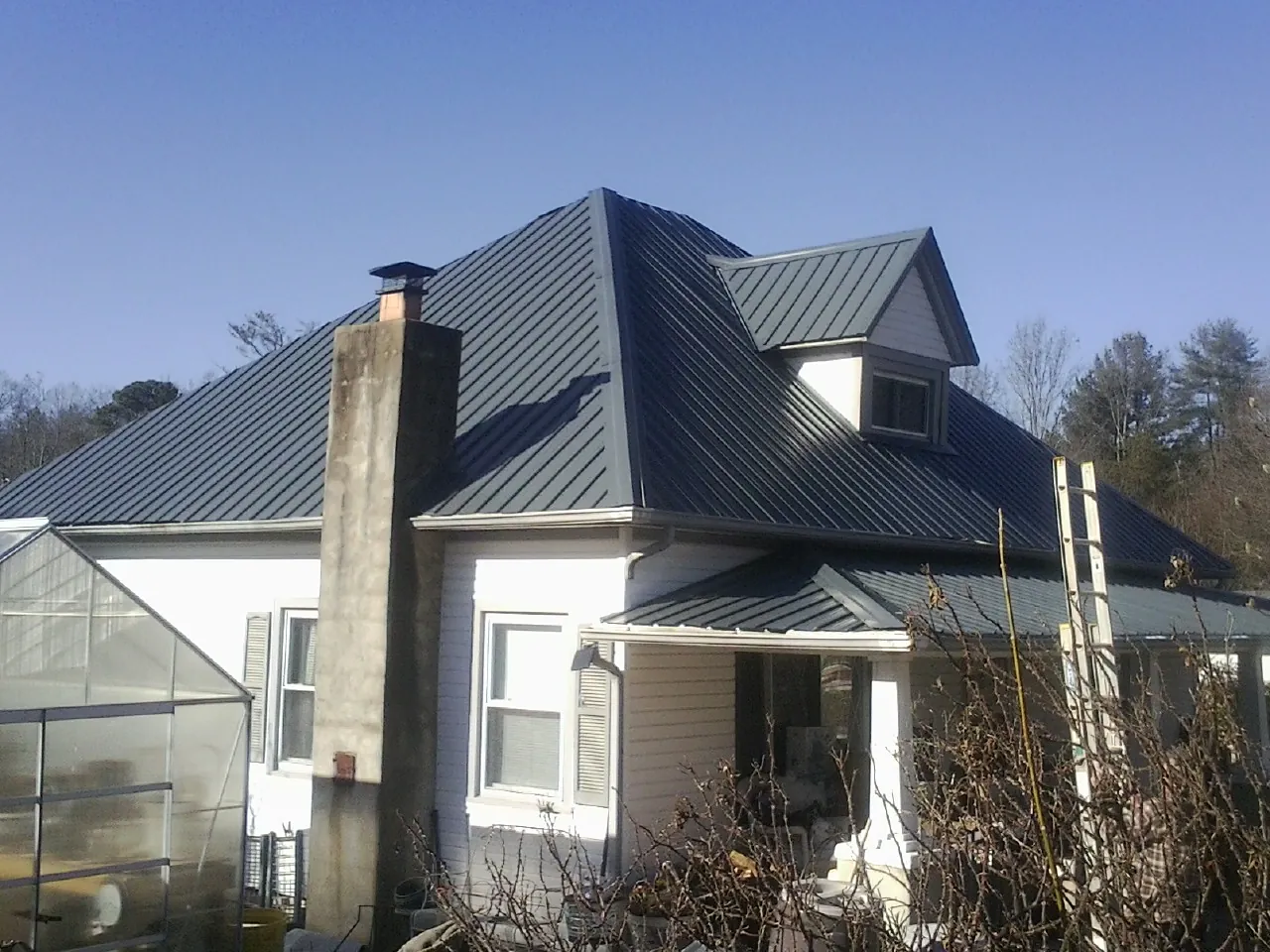Dark blue standing seam metal roof on a white farmhouse with dormer — Slate & Tile Roof Repair by Roofing Brothers in Rices Landing