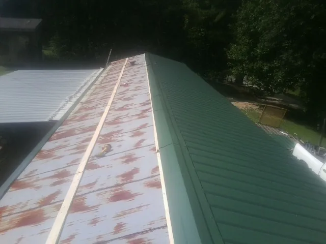 Old rusted panels beside newly installed green metal roofing — Wind Damage Roof Repair by Roofing Brothers in Rices Landing