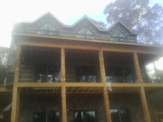 Dormers and porch framing on a large log home under construction — Roof Coating work by our crew in Rices Landing