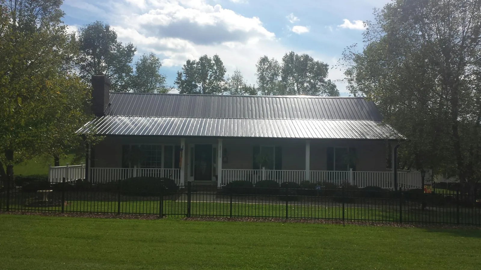 Gray metal roof on a brick ranch with a full width front porch — Gutter Guard Installation work by our crew in Rices Landing
