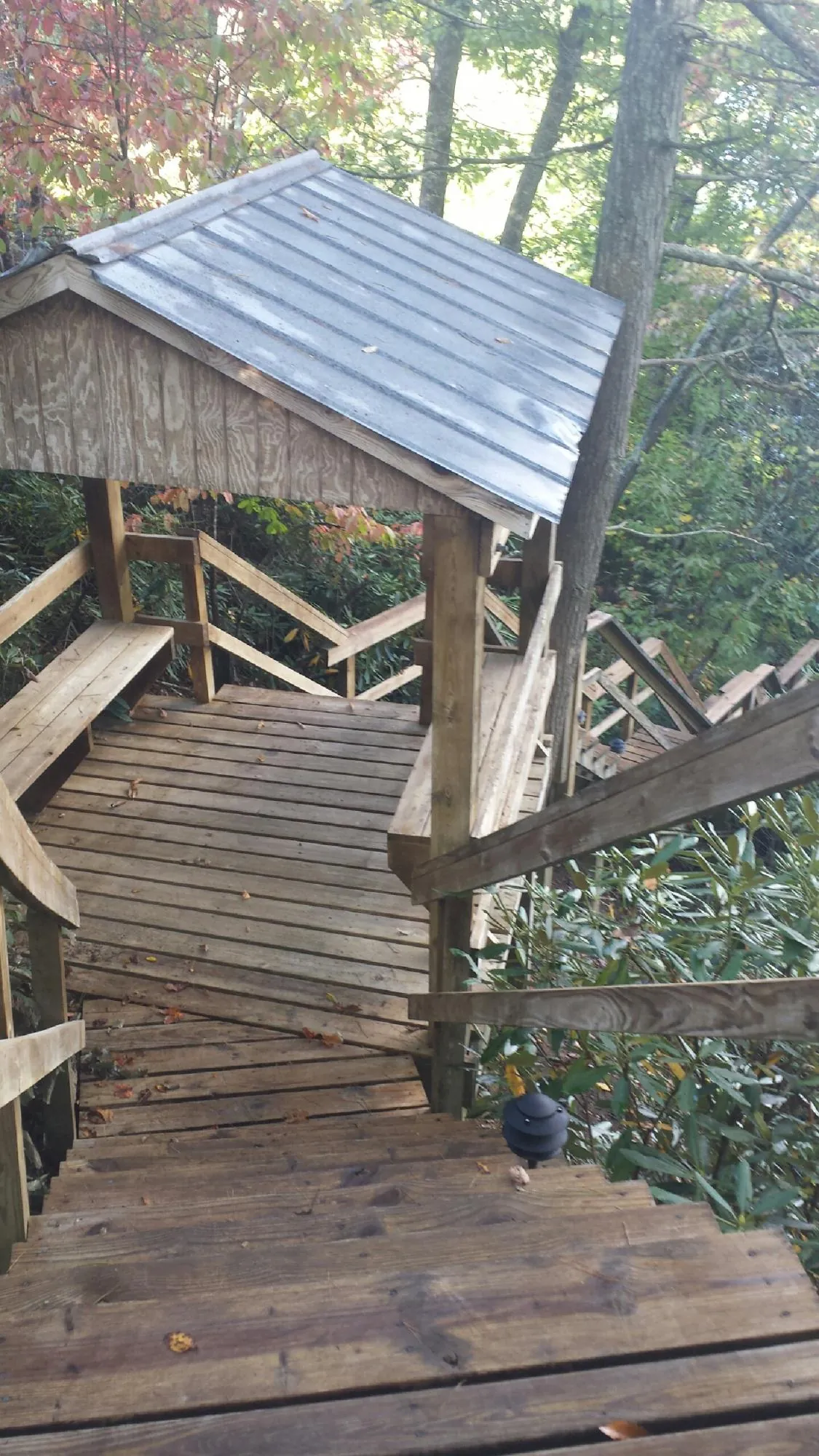 Metal roofed shelter over wooden steps on a wooded walkway — Skylight Repair & Installation work by our crew in Rices Landing