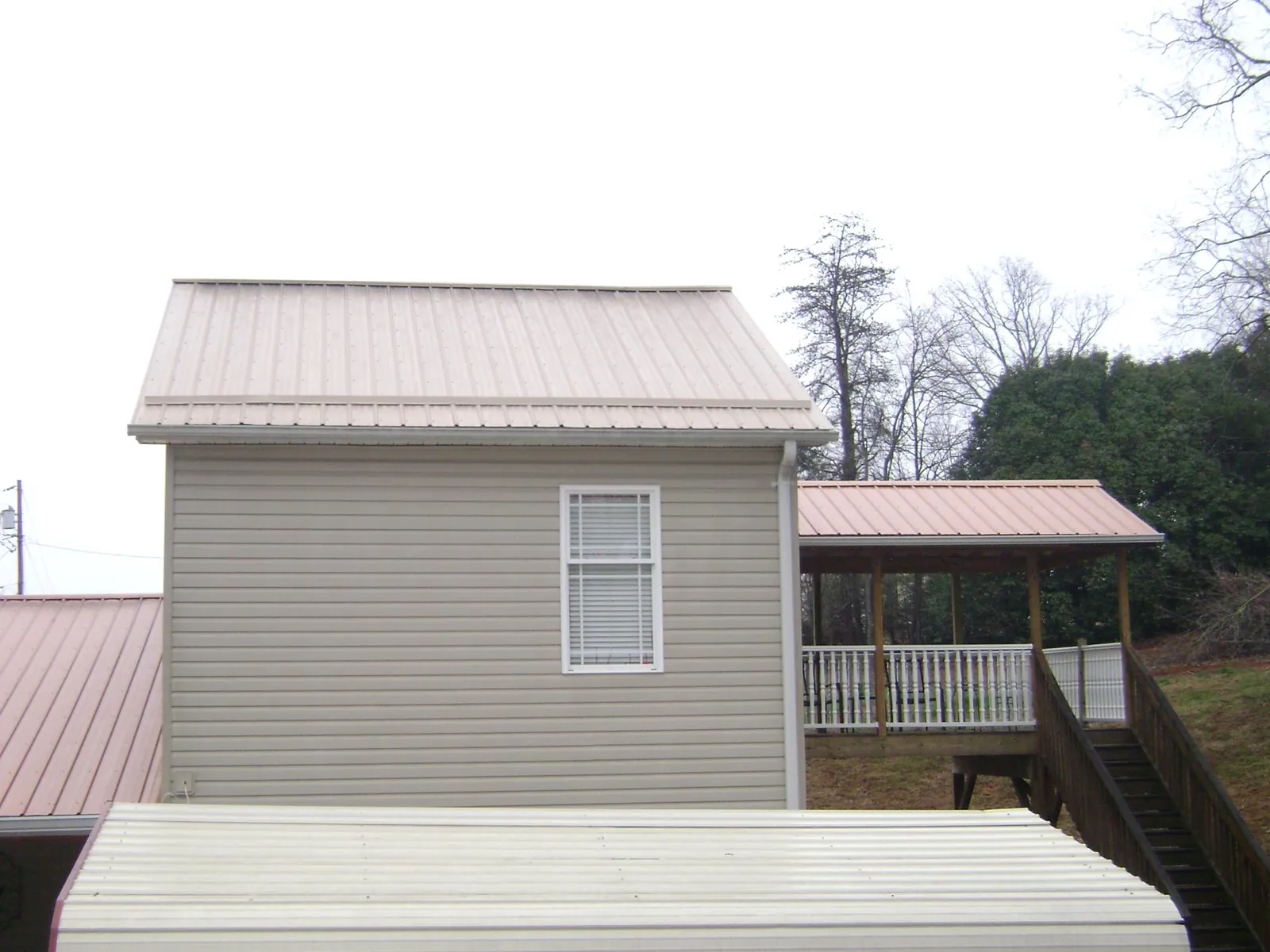 Tan metal roofs on a two story addition and attached porch, from a Roof Replacement job in Rices Landing