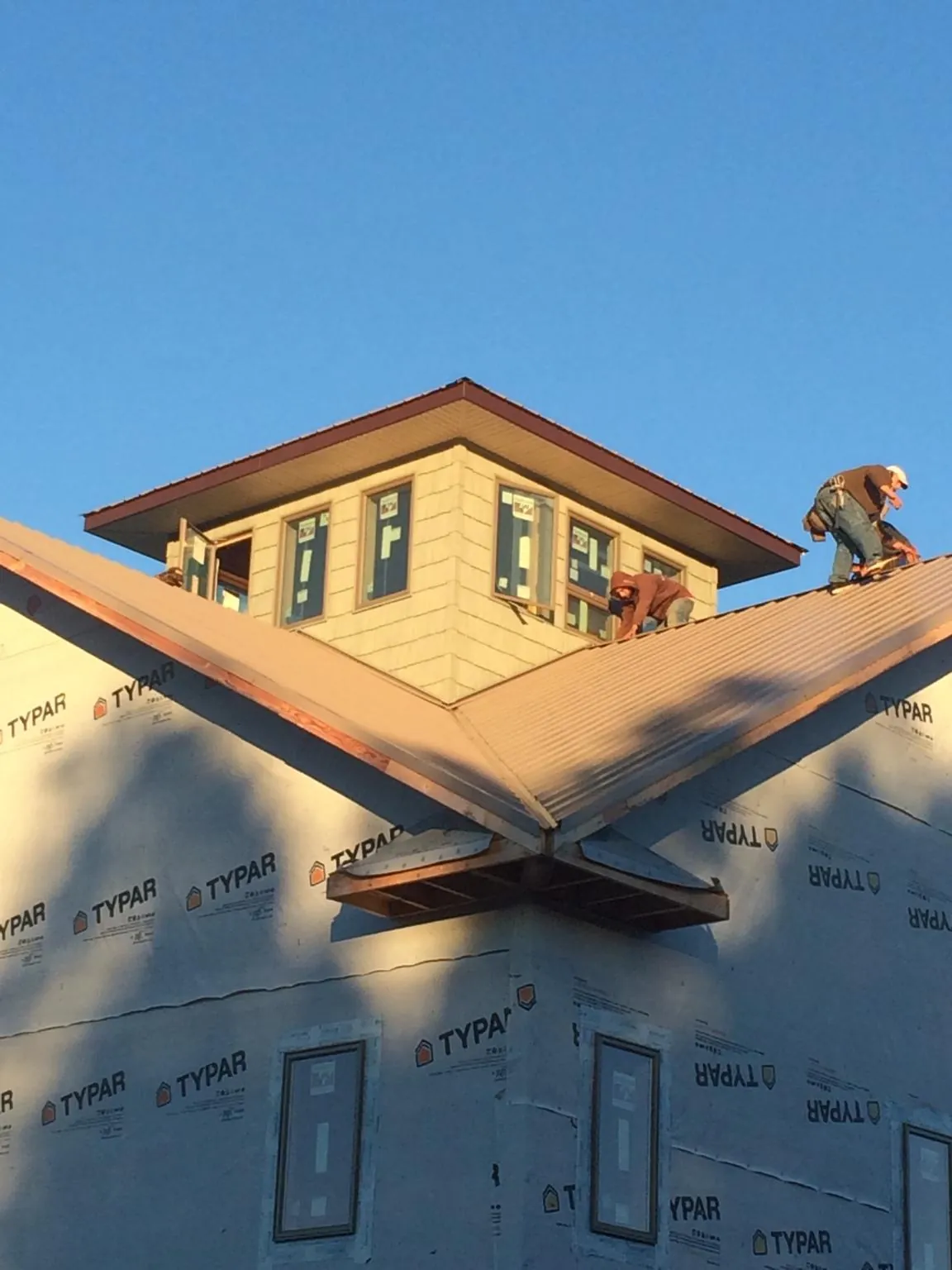 Roofers working around a rooftop cupola on a new metal roof at sunset — Roof Waterproofing in Rices Landing by Roofing Brothers